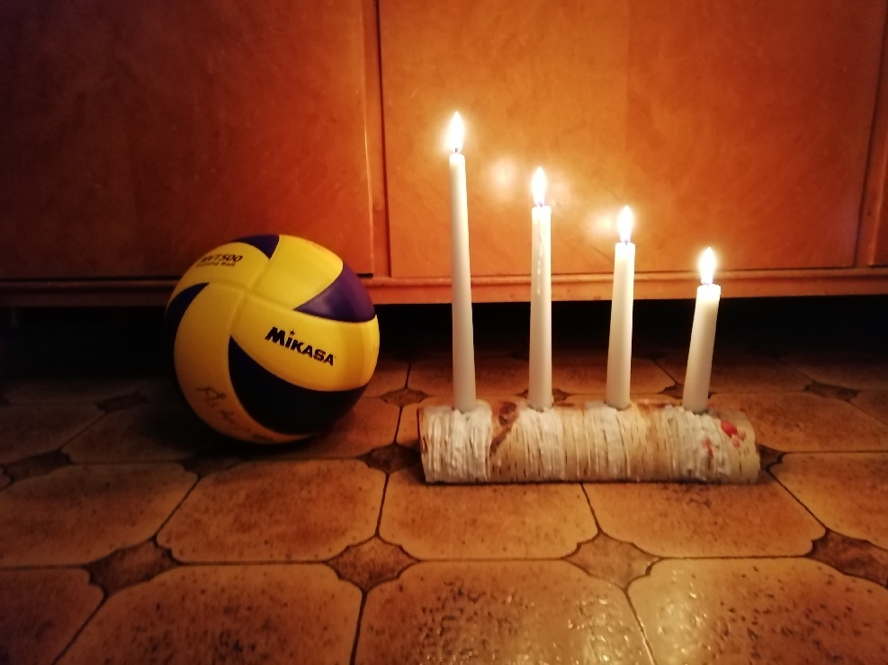 Volleyboll bredvid en adventsljusstake med fyra tända ljus.